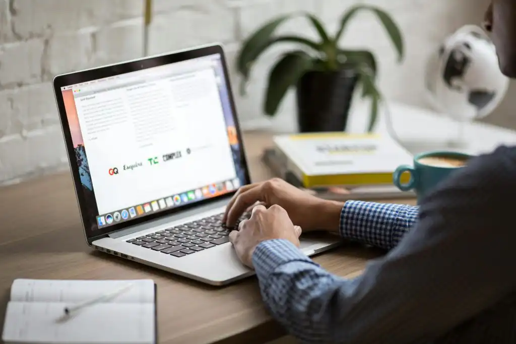 A man working on a laptop at a desk with coffee, showcasing remote work in a modern office setting.
