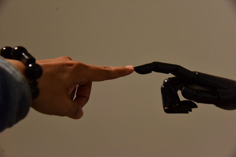 Eine menschliche Hand und eine robotische Hand berühren sich und stehen für den Artikel wie man gute Prompts schreiben kann