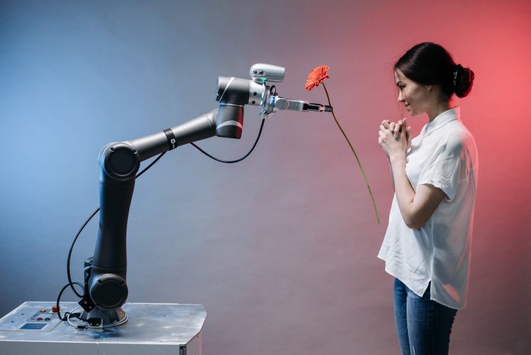 Ein Roboterarm überreicht einer Frau eine Blume und steht sinnbildlich für KI im Unternehmen einführen